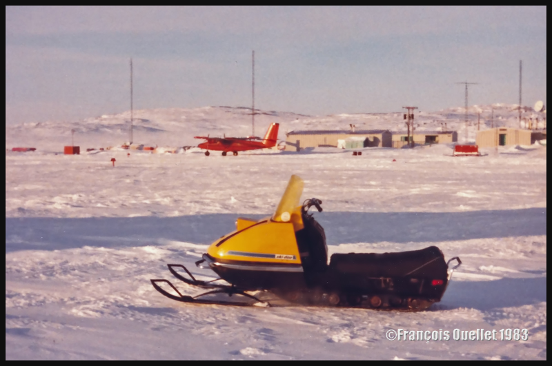 Le Twin Otter de Bell Canada, au second plan, lors d’une belle journée d’hiver à Inukjuak. Au premier plan, un modèle de ski-doo de l’époque.