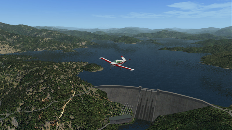 Le monomoteur en vol lent et train sorti au-dessus du barrage de Shasta aux États-Unis.