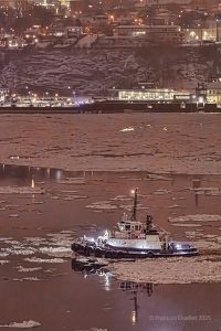 Ocean's tugboat on the St.Lawrence river in front of Quebec City in winter.