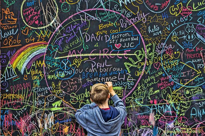 Un garçon écrit sur un mur à Boston, 2019.