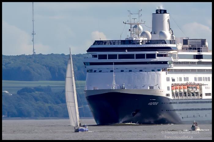 Un voilier et le navire de croisière Volendam sur le fleuve St-Laurent près de l'île d'Orléans lors de la Transat Québec St-Malo 2024.